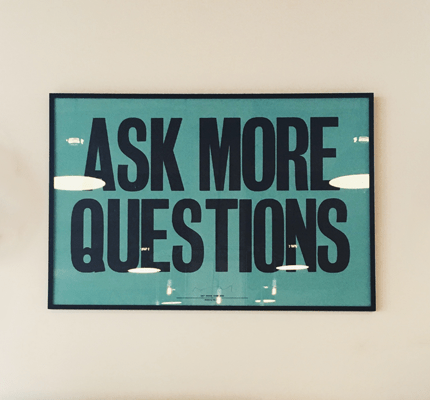 Poster on wall that says "Ask more questions"