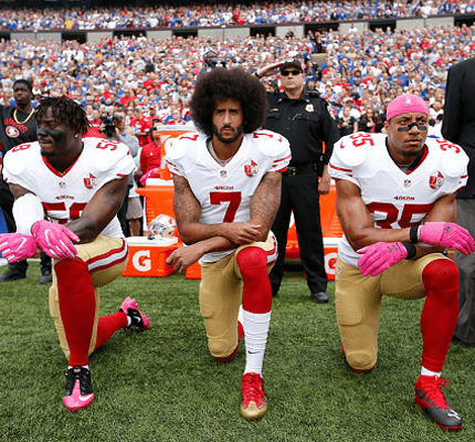 Three football players kneeling on one knee