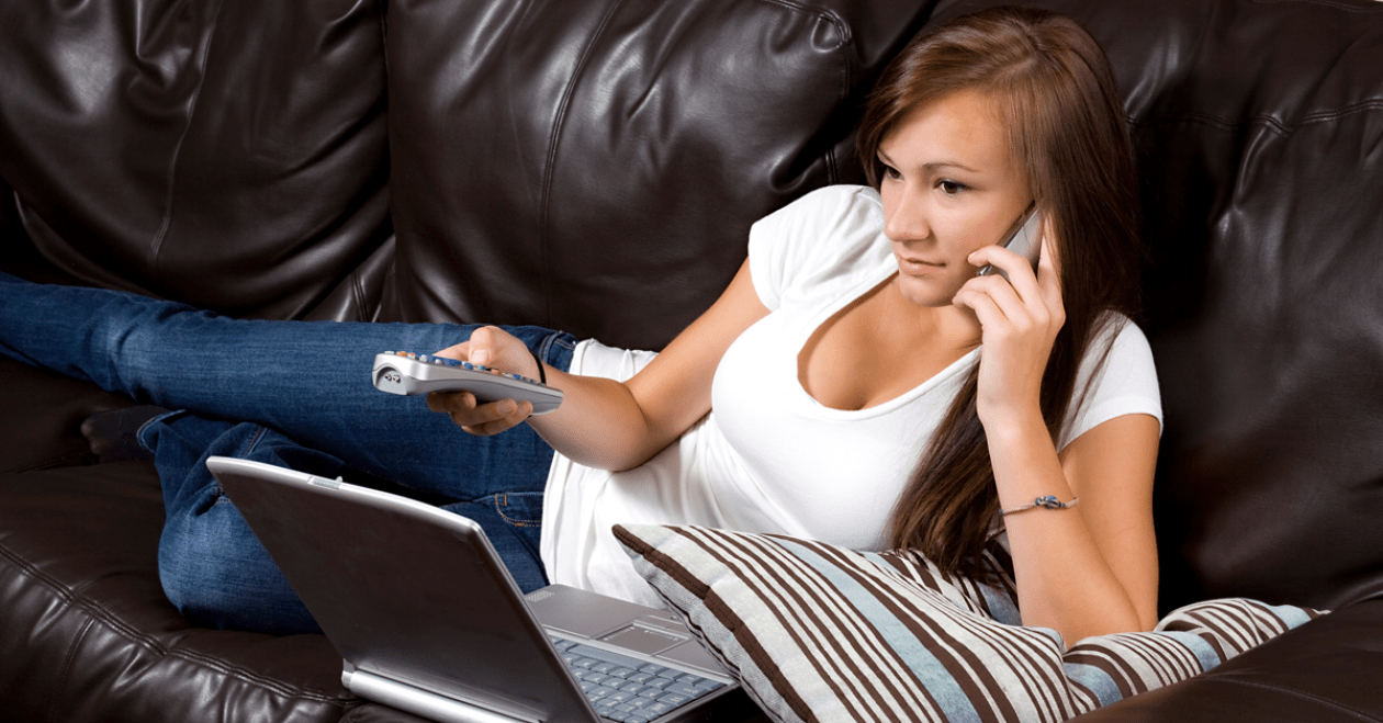 Woman watching TV while using laptop and phone