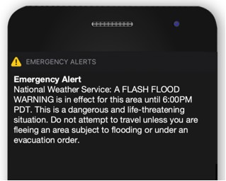 Phone screen showing an expanded Wireless Emergency Alert from the National Weather Service describing a dangerous and life-threatening flash flood situation and advising not to travel.